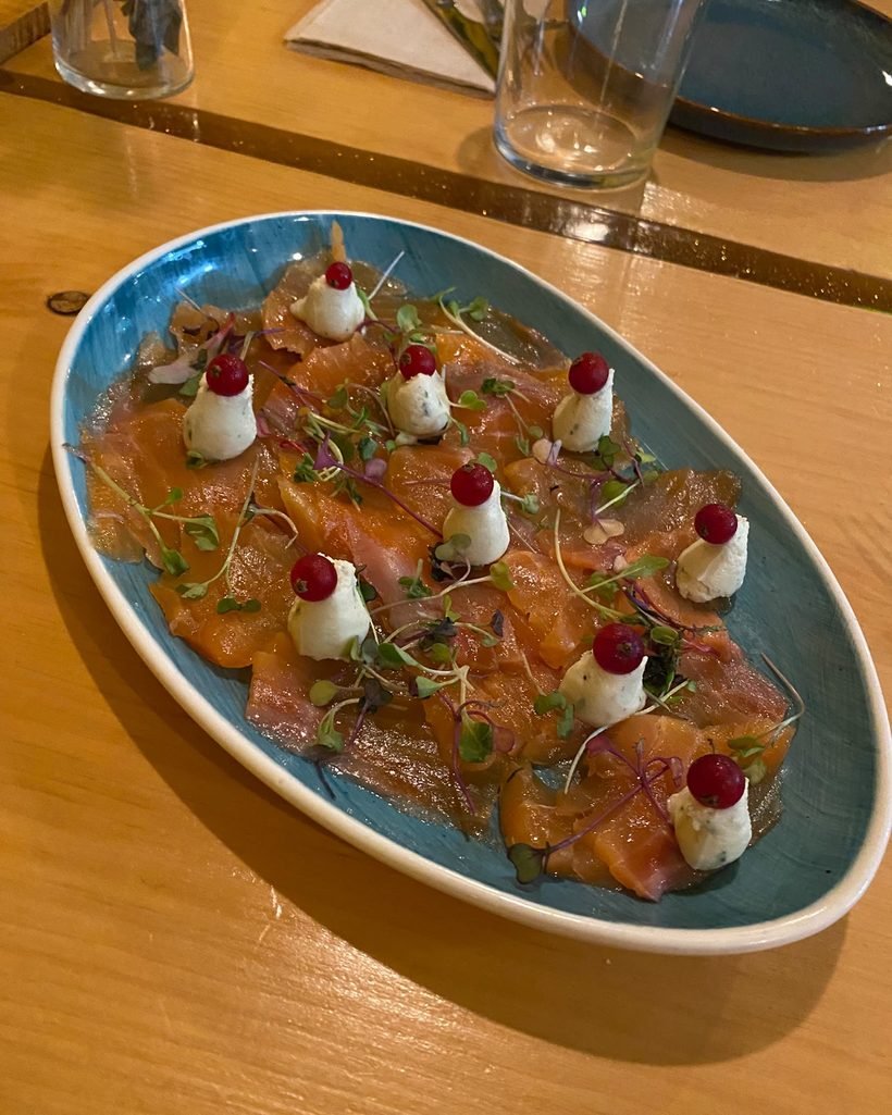 Carpaccio de salmón ahumado en casa con quenelles de burrata al limón, grosellas y brotes