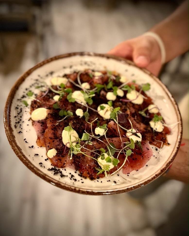 Carpaccio con brotes y crema, en plato redondo