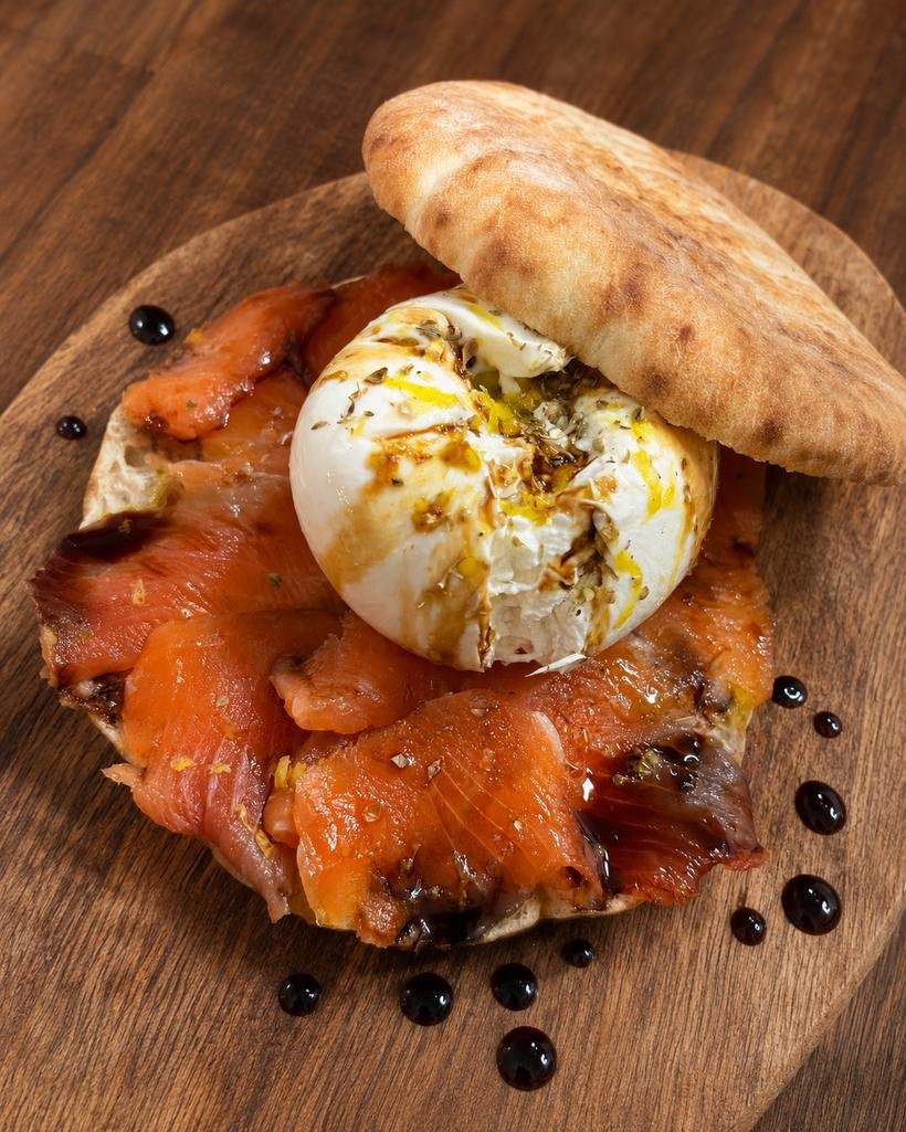 Focaccia pugliese filled with homemade smoked salmon and lemon burrata, on a wooden board
