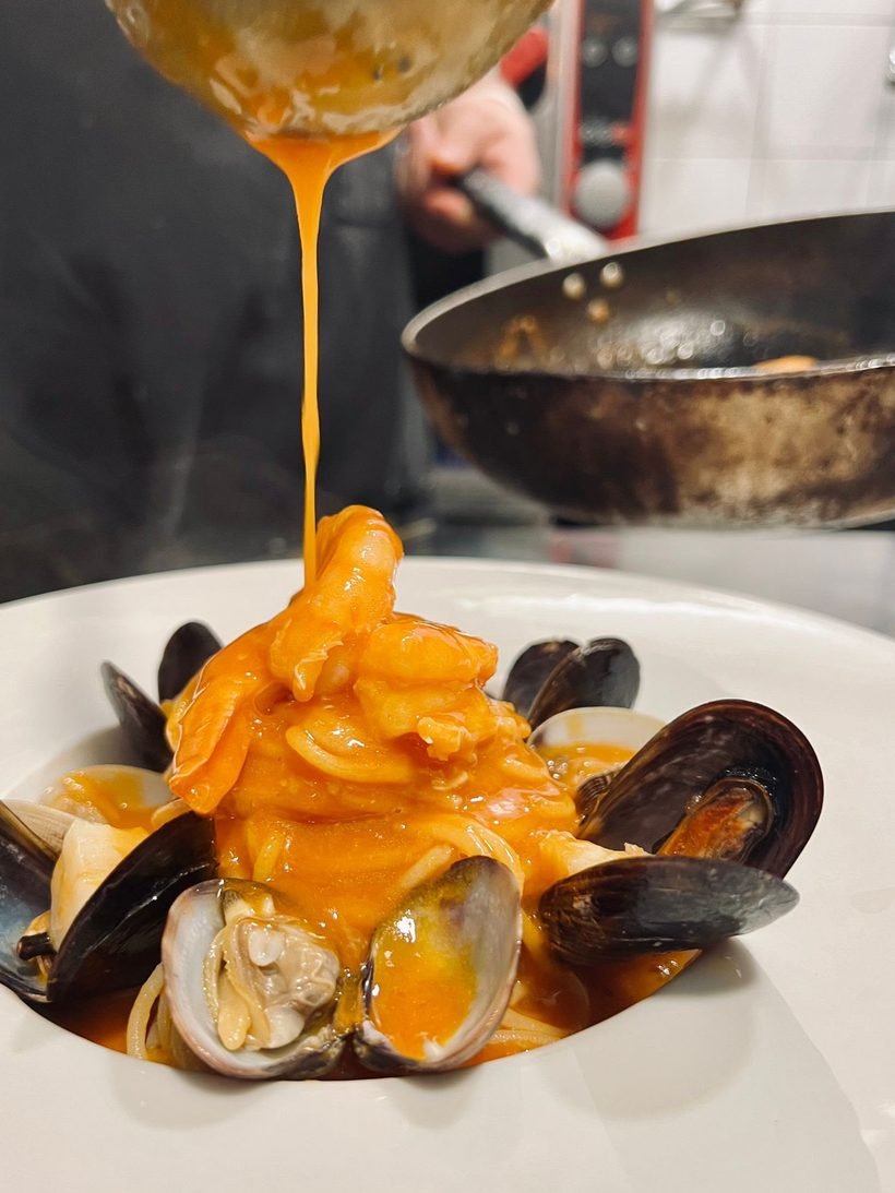 Salsa vertida sobre pasta con almejas y mejillones